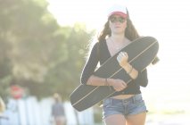 Jeune femme portant skateboard — Photo de stock