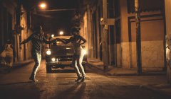 Чоловік і жінка танцюють разом перед класичною машиною на вулиці вночі . — стокове фото