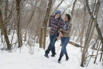Couple walking arm in arm through the winter woods. — Stock Photo