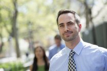 Man in suit looking away on street with unfocused people in background — Stock Photo