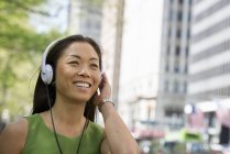 Mulher asiática ouvindo música com fones de ouvido na cidade — Fotografia de Stock