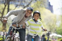 Африканский американский отец и сын катаются на велосипеде и веселятся в парке — стоковое фото
