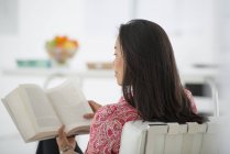Visão traseira da mulher sentada e livro de leitura — Fotografia de Stock