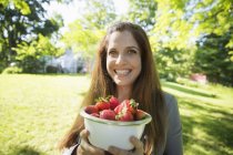 Frau trägt Schale mit frisch gepflückten Bio-Erdbeeren. — Stockfoto