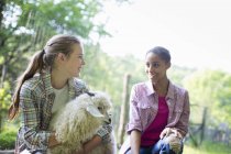 Two young women on farm with very fluffy angora goat. — Stock Photo