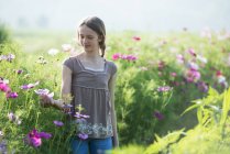 Adolescente menina tocando flores no campo — Fotografia de Stock