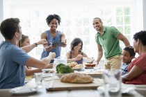 Family of men, women and children sharing meal at dining table. — Stock Photo