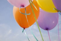 Un mucchio di palloncini colorati che galleggiano in aria contro il cielo blu . — Foto stock
