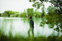 Hombre de pie y mirando a la vista a través del agua del lago . - foto de stock