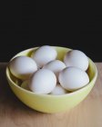 Cuenco de huevos blancos ecológicos en la mesa - foto de stock