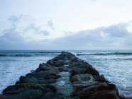 Seascape and groyne built out of rocks onto water in San Diego, USA. — Stock Photo
