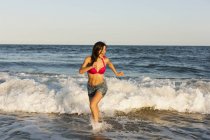 Young woman running at water edge on beach in Atlantic City, USA. — Stock Photo