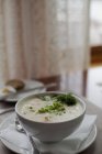 Tigela branca de sopa com guarnição em guardanapo de mesa . — Fotografia de Stock