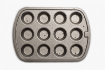 Well used seasoned muffin tin on white background. — Stock Photo