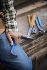 Cropped view of man sitting at workbench with grippers and pliers lined up on plank of wood. — Stock Photo