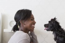Teenage girl playing with small black pet dog, side view. — Stock Photo