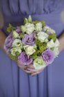 Cropped view of bridesmaid in blue dress holding bouquet of roses. — Stock Photo