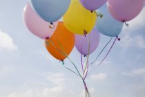 Куча разноцветных воздушных шаров, плавающих в воздухе против голубого неба . — стоковое фото