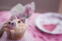 Cupcake decorato con immagine di maiale sul tavolo decorato con colore rosa . — Foto stock