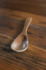 Smooth polished wooden spoon on  grained wooden tabletop. — Stock Photo