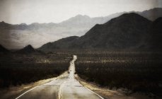 Road leading range of mountains with desert scenery and cars. — Stock Photo