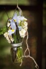 Glass jar hanging from wire with iris and scented white flowers. — Stock Photo