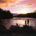 Двоє людей стоять на березі і рибалять у сутінках . — стокове фото