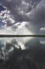 Reflection of dramatic sky in flat surface of lake. — Stock Photo