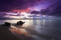 Захід сонця з помаранчевим і фіолетовим небом, що відображається у спокійній воді . — стокове фото
