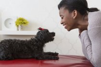 Teenage girl playing with small black pet dog at home. — Stock Photo