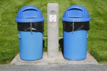 Latas de basura azul en el campo de deportes de hierba . - foto de stock