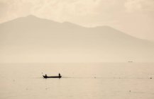 Kleines Fischerboot mit zwei Personen auf dem Chapala-See mit Bergen im Hintergrund, Mexiko. — Stockfoto