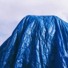 Blue tarpaulin draped against blue sky, cropped. — Stock Photo