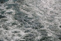 Turbulente Wasseroberfläche mit Wellen und Blasen, Vollbild. — Stockfoto