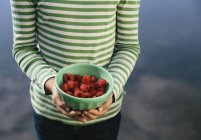 Cropped view of girl holding bowl of organic raspberries — Stock Photo