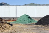 Piles of green and black bark wood chips by fence near Quincy, Washington, USA. — Stock Photo