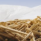 White tarp covering pile of wooden studs used for construction. — Stock Photo