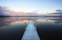 Muelle sobre el agua del lago tranquilo al atardecer en Saskatchewan, Canadá . - foto de stock