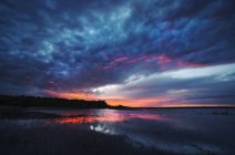 Coucher de soleil sur l'eau calme du lac avec un paysage nuageux crépusculaire au Manitoba, Canada . — Photo de stock