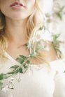 Vista cortada de mulher loira sorrindo com guirlanda floral em torno dos ombros . — Fotografia de Stock