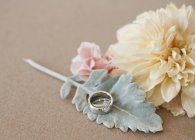 Flores, hojas y anillos de boda sobre fondo liso, primer plano . - foto de stock