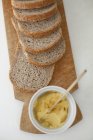 Papelão de madeira com pão integral fatiado e prato de manteiga . — Fotografia de Stock