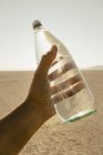 Bottiglia d'acqua tenuta in mano maschile nel paesaggio del deserto di Black Rock in Nevada — Foto stock