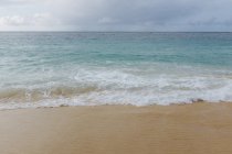 Долаючи хвилі на піску на березі Тихого океану. — стокове фото