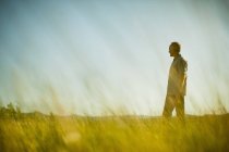 Mature man standing in grassland and looking at view in field. — Stock Photo