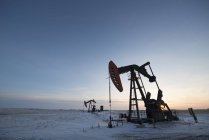 Нафти буріння Ріг і верстат-качалка на плоскою рівнині в канадських нафтового родовища на заході сонця. — стокове фото