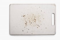 Used silicon cutting board with crumbs and knife marks in white background — Stock Photo