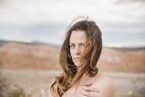 Жінка з довгим коричневим волоссям, що стоїть в пустельному пейзажі . — стокове фото