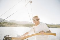 Porträt eines blonden Mannes mit Sonnenbrille am Steuer eines Segelbootes. — Stockfoto