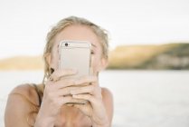 Mujer joven rubia tomando fotos con teléfono móvil . - foto de stock